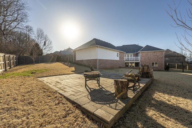 rear view of property featuring brick siding, a patio, a fenced backyard, and a lawn