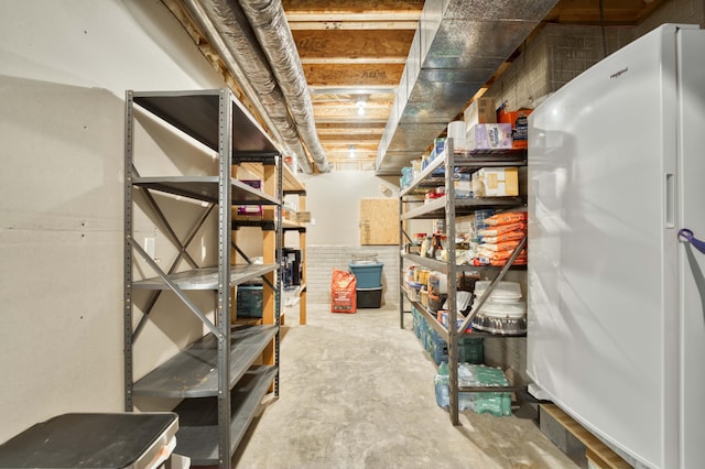 unfinished basement featuring freestanding refrigerator