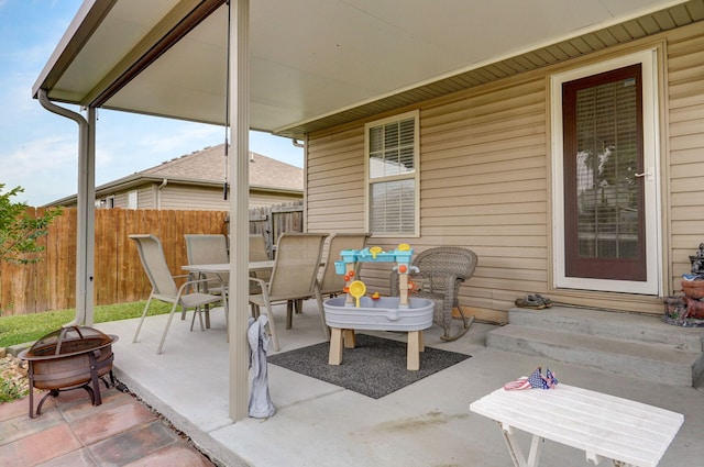 view of patio / terrace with a fire pit, outdoor dining space, entry steps, and fence