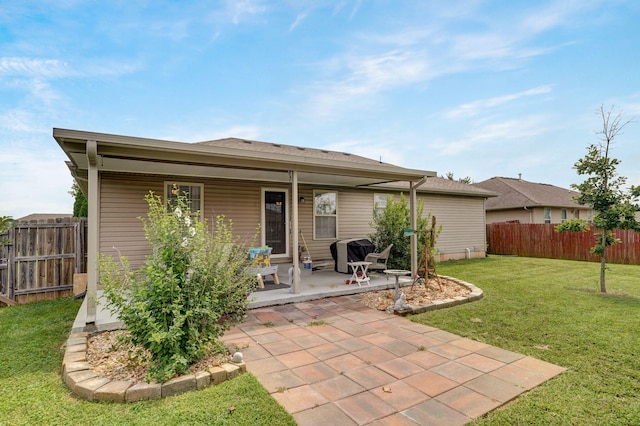 rear view of property featuring a lawn, a patio, and fence