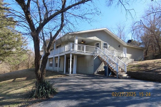 view of front facade with aphalt driveway, stairway, a wooden deck, and ceiling fan