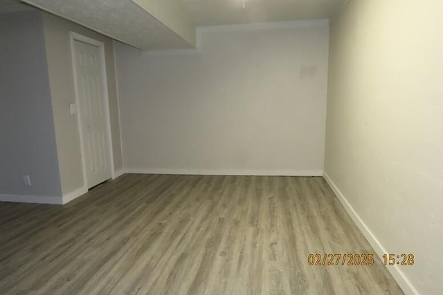 spare room with wood finished floors, baseboards, and ornamental molding