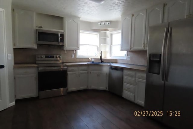 kitchen with a sink, dark wood-type flooring, appliances with stainless steel finishes, and white cabinetry