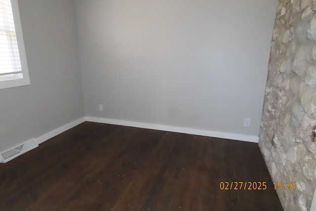 unfurnished room with wood finished floors, visible vents, and baseboards