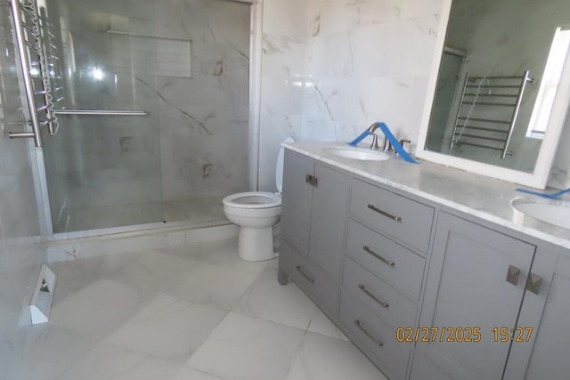 bathroom with a marble finish shower, double vanity, a sink, toilet, and marble finish floor