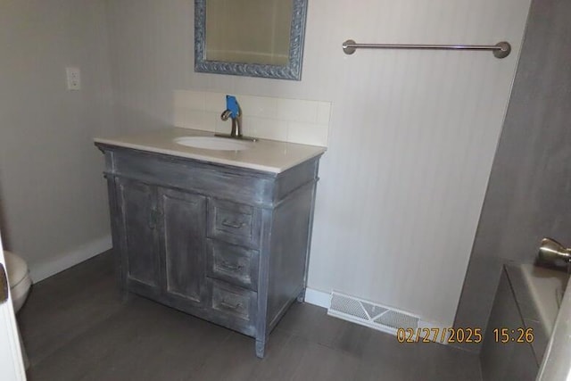 bathroom with visible vents, vanity, baseboards, and decorative backsplash