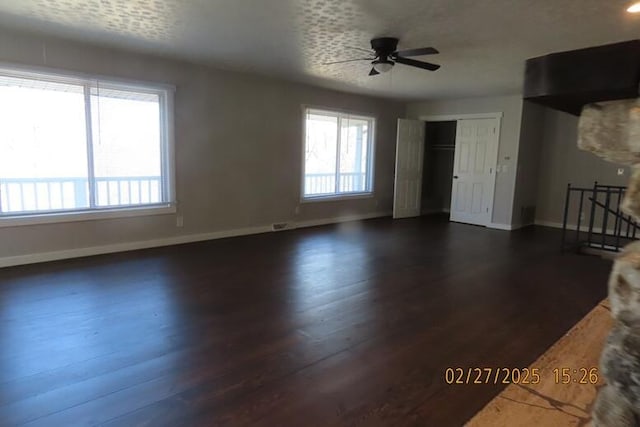 unfurnished living room with dark wood finished floors, plenty of natural light, and baseboards