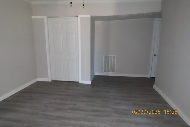 empty room featuring visible vents, baseboards, and dark wood-style flooring