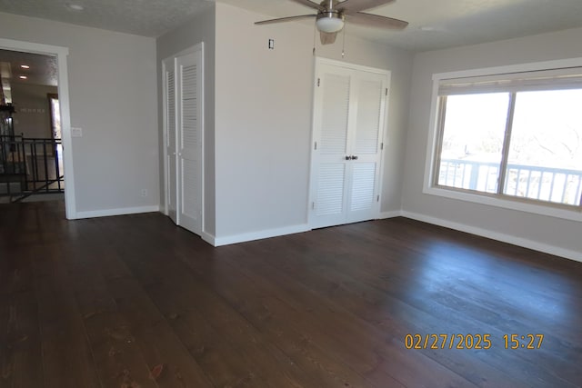 interior space with dark wood finished floors, a ceiling fan, and baseboards