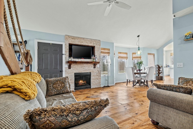 living area with lofted ceiling, a fireplace, arched walkways, a ceiling fan, and wood-type flooring