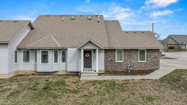 view of front facade featuring a front lawn, brick siding, and a shingled roof