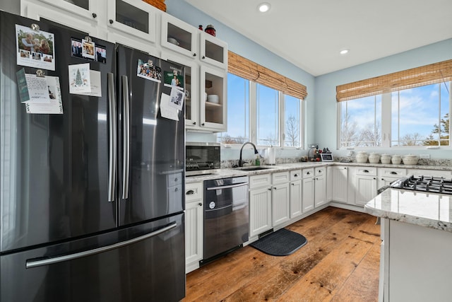 kitchen featuring freestanding refrigerator, a sink, white cabinets, glass insert cabinets, and dishwasher