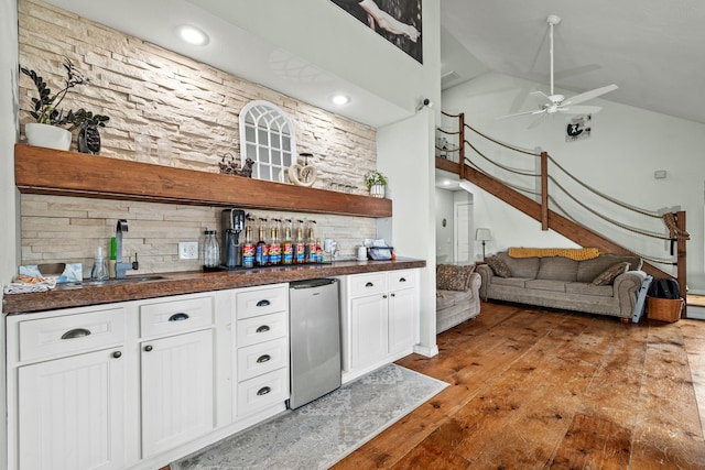 bar featuring stairway, a dry bar, vaulted ceiling, freestanding refrigerator, and light wood-style floors