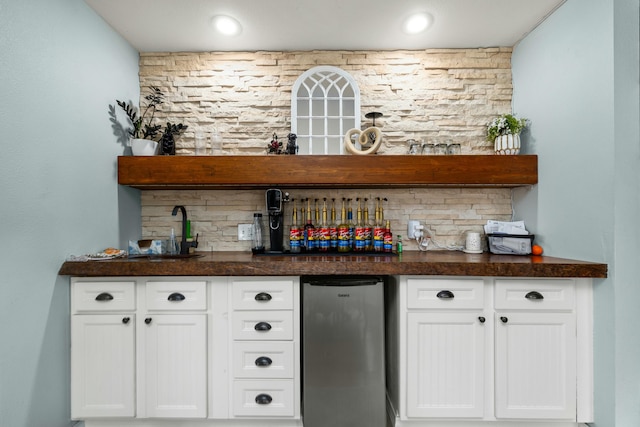 bar with backsplash, bar, and freestanding refrigerator