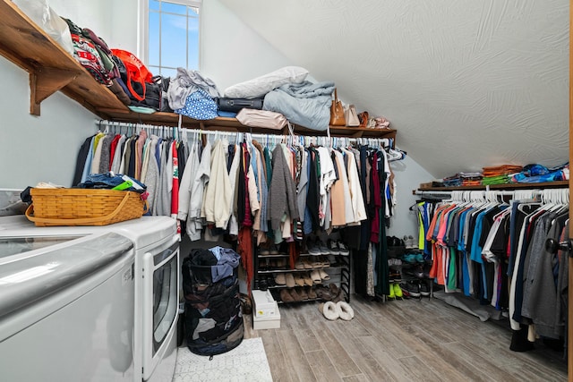 walk in closet featuring vaulted ceiling, wood finished floors, and separate washer and dryer