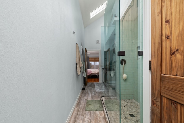 full bathroom with lofted ceiling with skylight, wood finished floors, connected bathroom, a shower stall, and baseboards