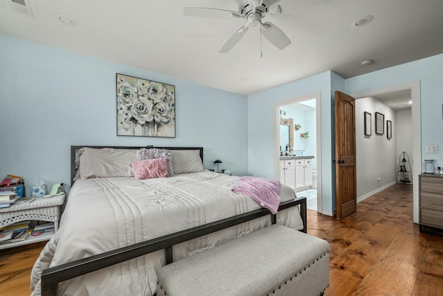 bedroom featuring visible vents, baseboards, hardwood / wood-style floors, ensuite bath, and a ceiling fan