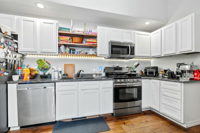 kitchen featuring wood finished floors, white cabinets, stainless steel appliances, and a sink