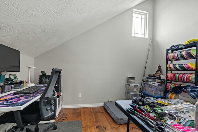 office area featuring vaulted ceiling, a textured ceiling, baseboards, and wood finished floors