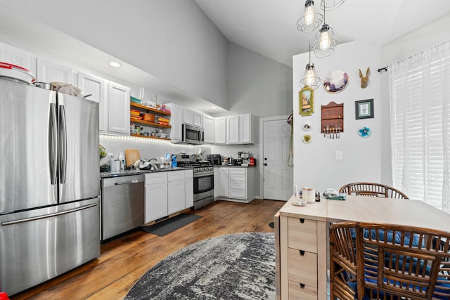 kitchen with wood finished floors, open shelves, appliances with stainless steel finishes, white cabinetry, and dark countertops