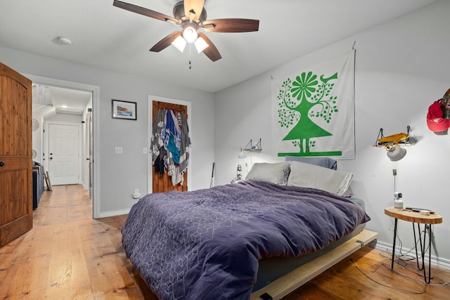 bedroom featuring a ceiling fan, baseboards, a spacious closet, a closet, and light wood-type flooring