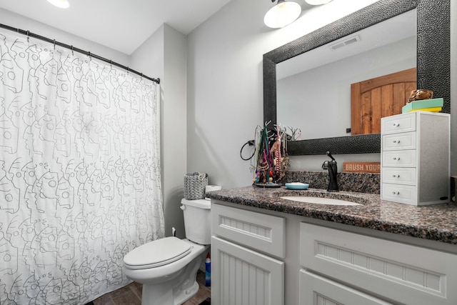 bathroom with visible vents, toilet, a shower with curtain, wood finished floors, and vanity