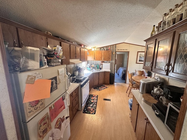 kitchen featuring light wood-type flooring, range hood, white appliances, light countertops, and vaulted ceiling