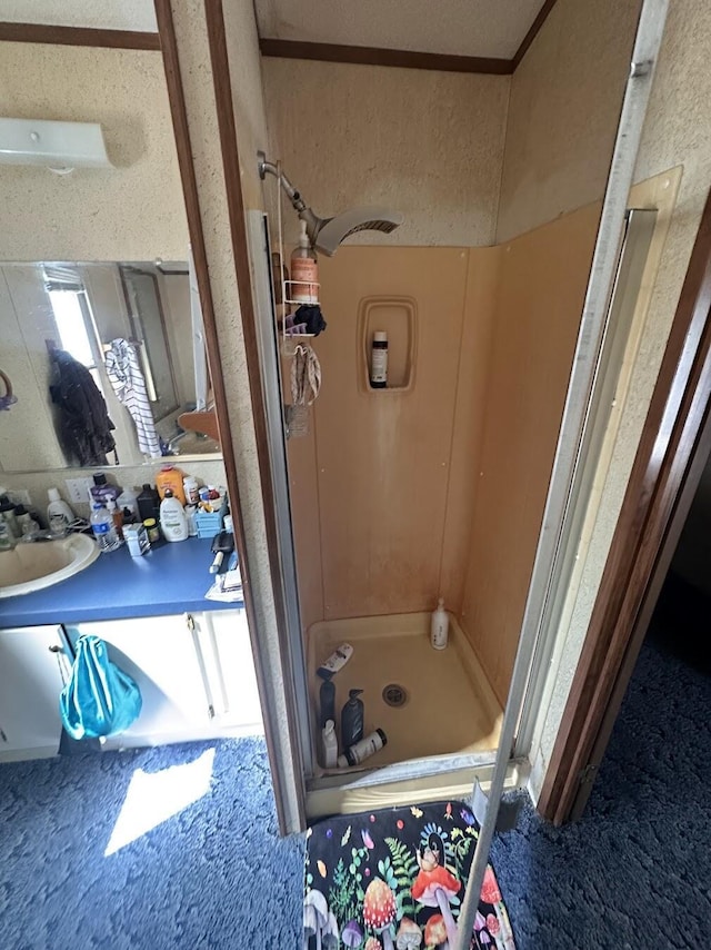 bathroom with vanity, a shower stall, and ornamental molding