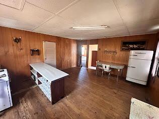 kitchen with wooden walls, wood finished floors, and freestanding refrigerator