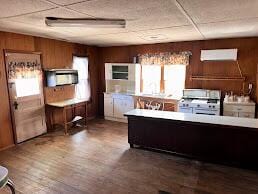 kitchen featuring wood walls, stainless steel stove, and wood finished floors