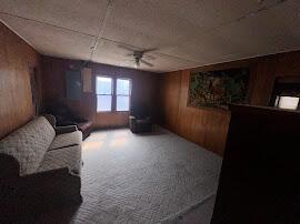 sitting room featuring wood walls and ceiling fan