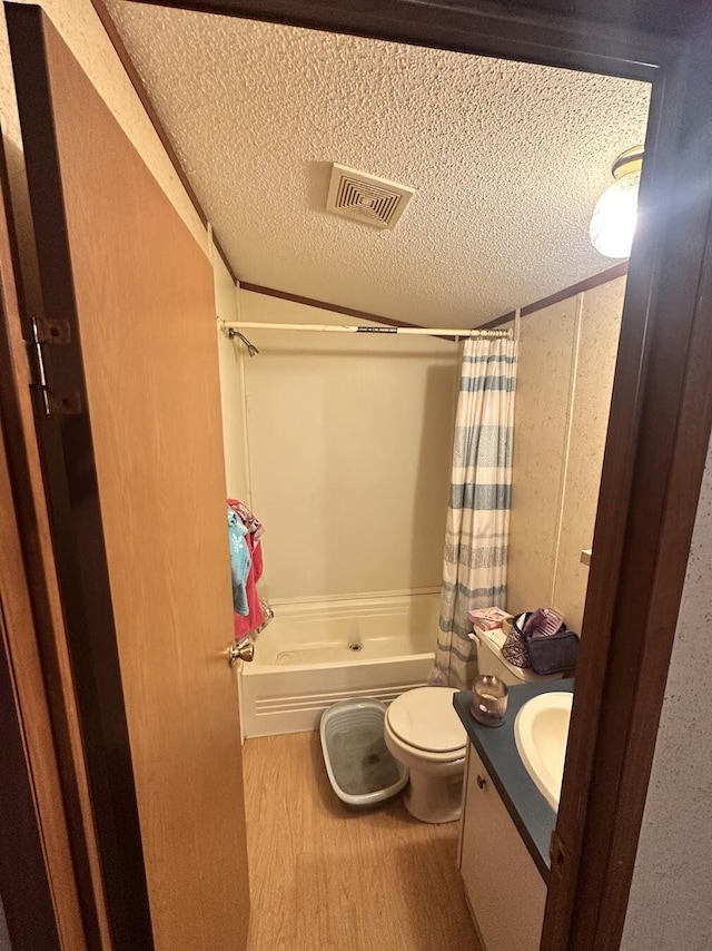 full bathroom featuring visible vents, toilet, a textured ceiling, wood finished floors, and vanity