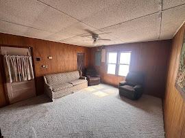 unfurnished living room featuring carpet, wood walls, and ceiling fan