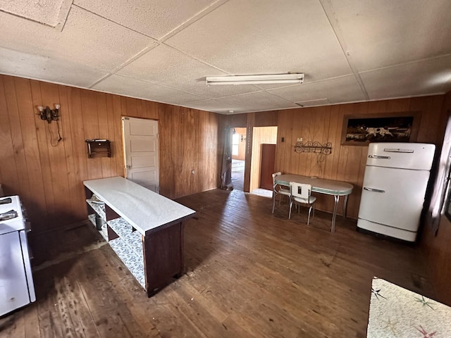 kitchen featuring washer / dryer, freestanding refrigerator, dark wood-type flooring, light countertops, and wood walls