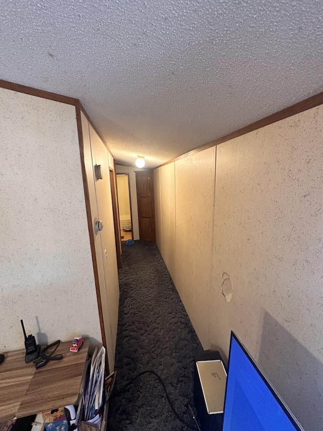 corridor featuring carpet flooring, a textured wall, and a textured ceiling