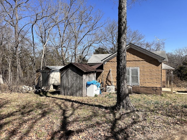 view of side of home featuring brick siding, a shed, and an outbuilding