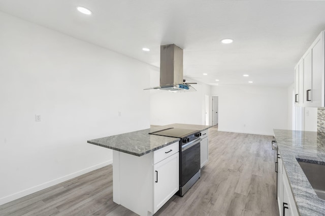 kitchen featuring dark stone countertops, range with electric stovetop, island exhaust hood, and light wood-type flooring