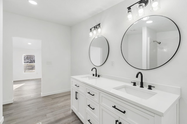 bathroom with a sink, baseboards, wood finished floors, and double vanity