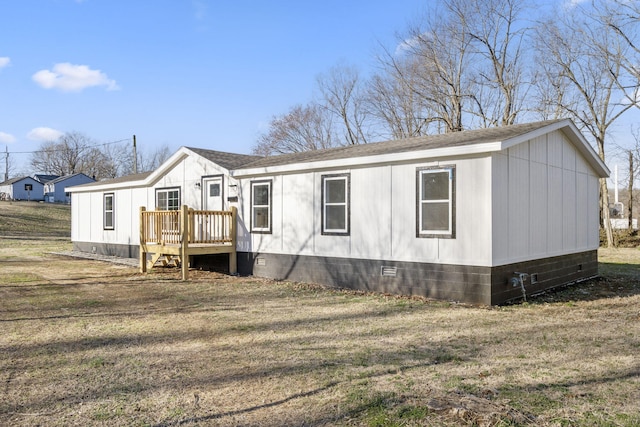 view of front of home with crawl space, roof with shingles, a deck, and a front yard