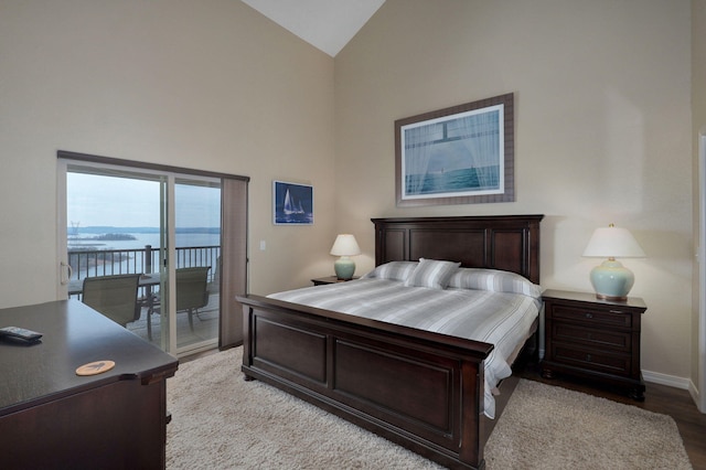 bedroom featuring light wood finished floors, a water view, baseboards, access to outside, and high vaulted ceiling