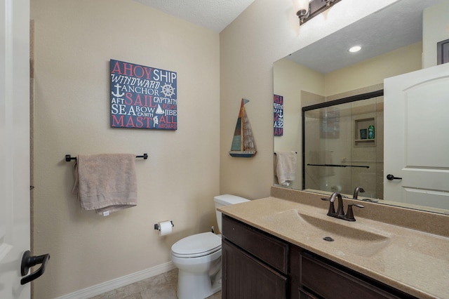 bathroom with toilet, a stall shower, vanity, baseboards, and tile patterned flooring