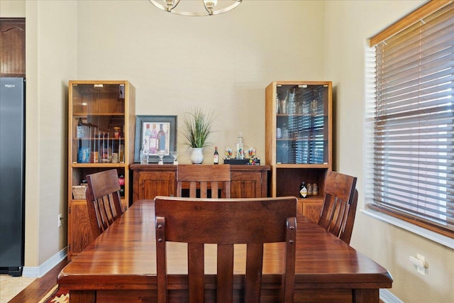 dining room with wood finished floors, a healthy amount of sunlight, baseboards, and an inviting chandelier
