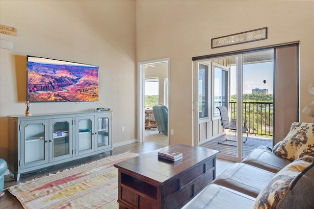 living room with a high ceiling, light wood-style flooring, and baseboards