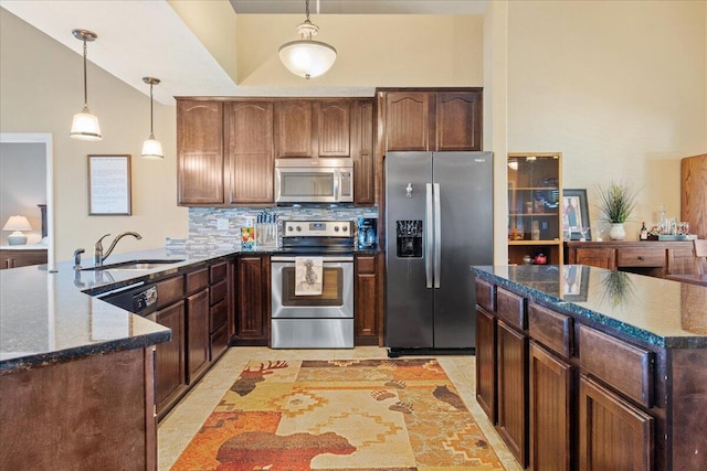 kitchen featuring a sink, decorative backsplash, decorative light fixtures, a peninsula, and appliances with stainless steel finishes