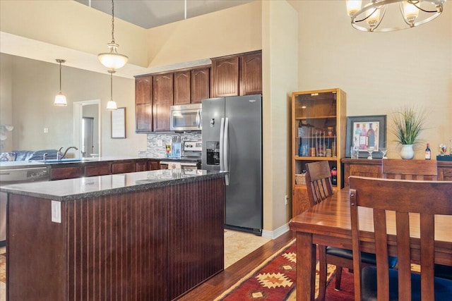 kitchen featuring a sink, light wood-type flooring, a notable chandelier, appliances with stainless steel finishes, and hanging light fixtures