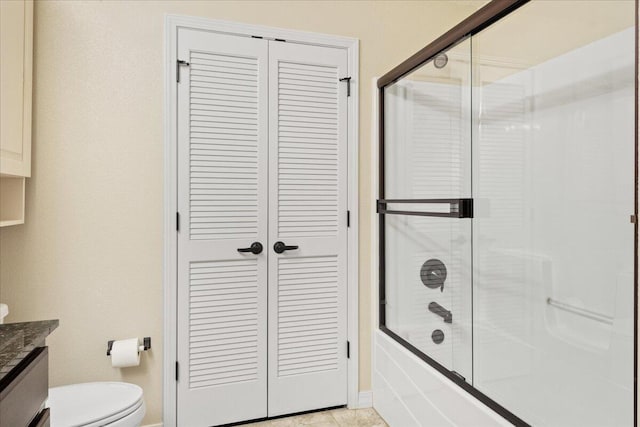 bathroom featuring a closet, toilet, vanity, and enclosed tub / shower combo
