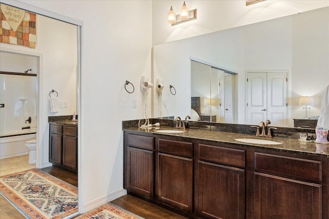bathroom with double vanity, toilet, shower / bathtub combination, and a sink