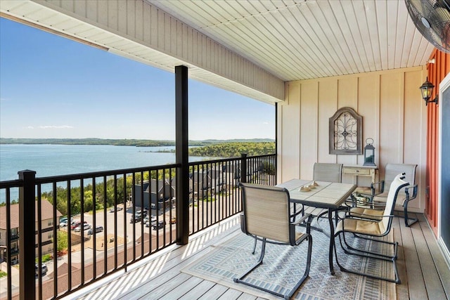balcony with outdoor dining space and a water view