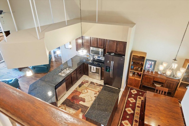 kitchen featuring dark brown cabinets, a sink, stainless steel appliances, a peninsula, and a notable chandelier