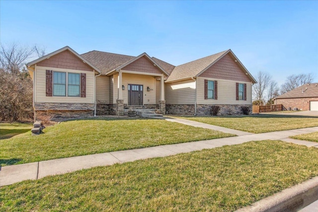 craftsman inspired home with stone siding, a front lawn, and roof with shingles